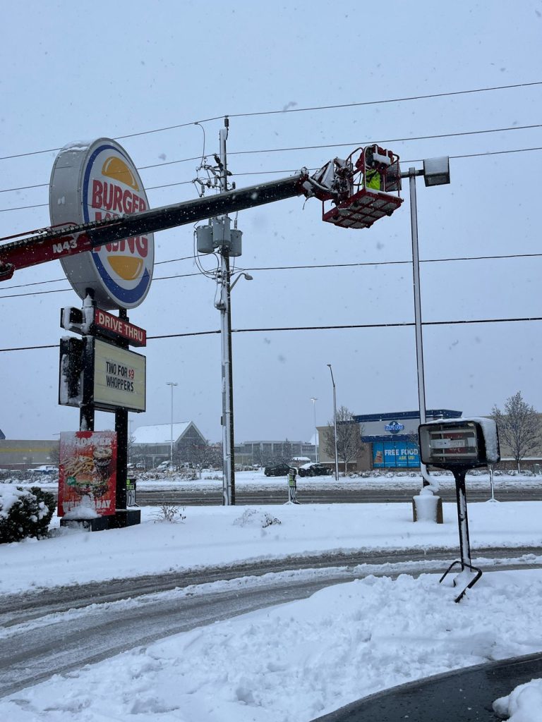 a photo of a burger king sign with YESCO bucket ladder with snow on the ground