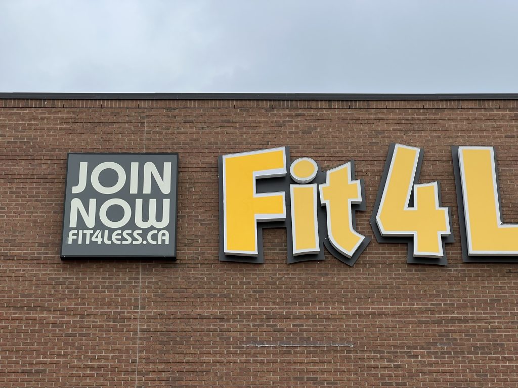 Fit 4 Less sign on brick wall