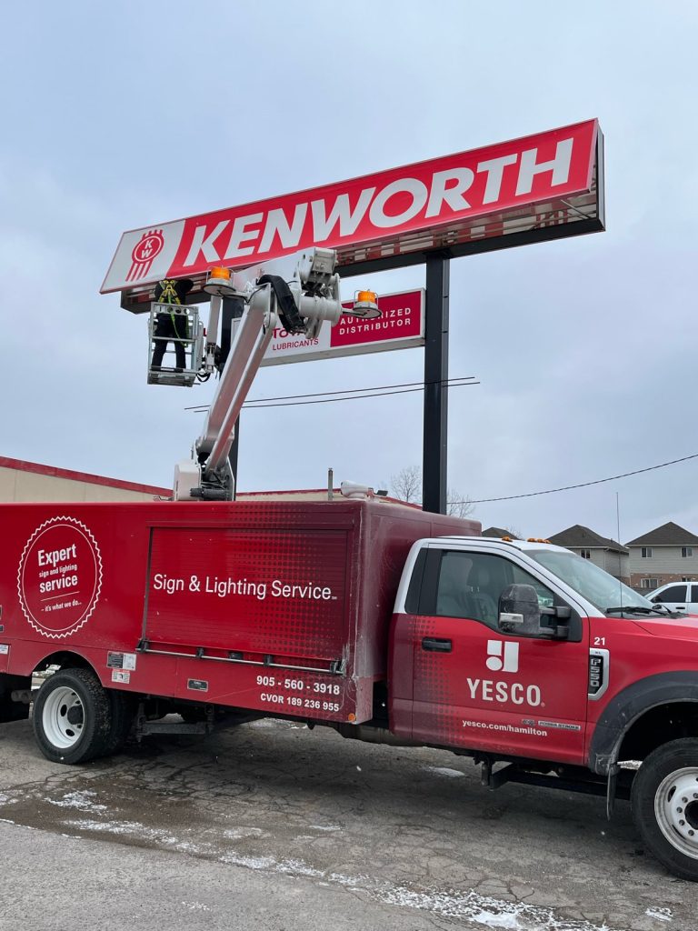 red and white Kenworth business sign with YESCO truck servicing