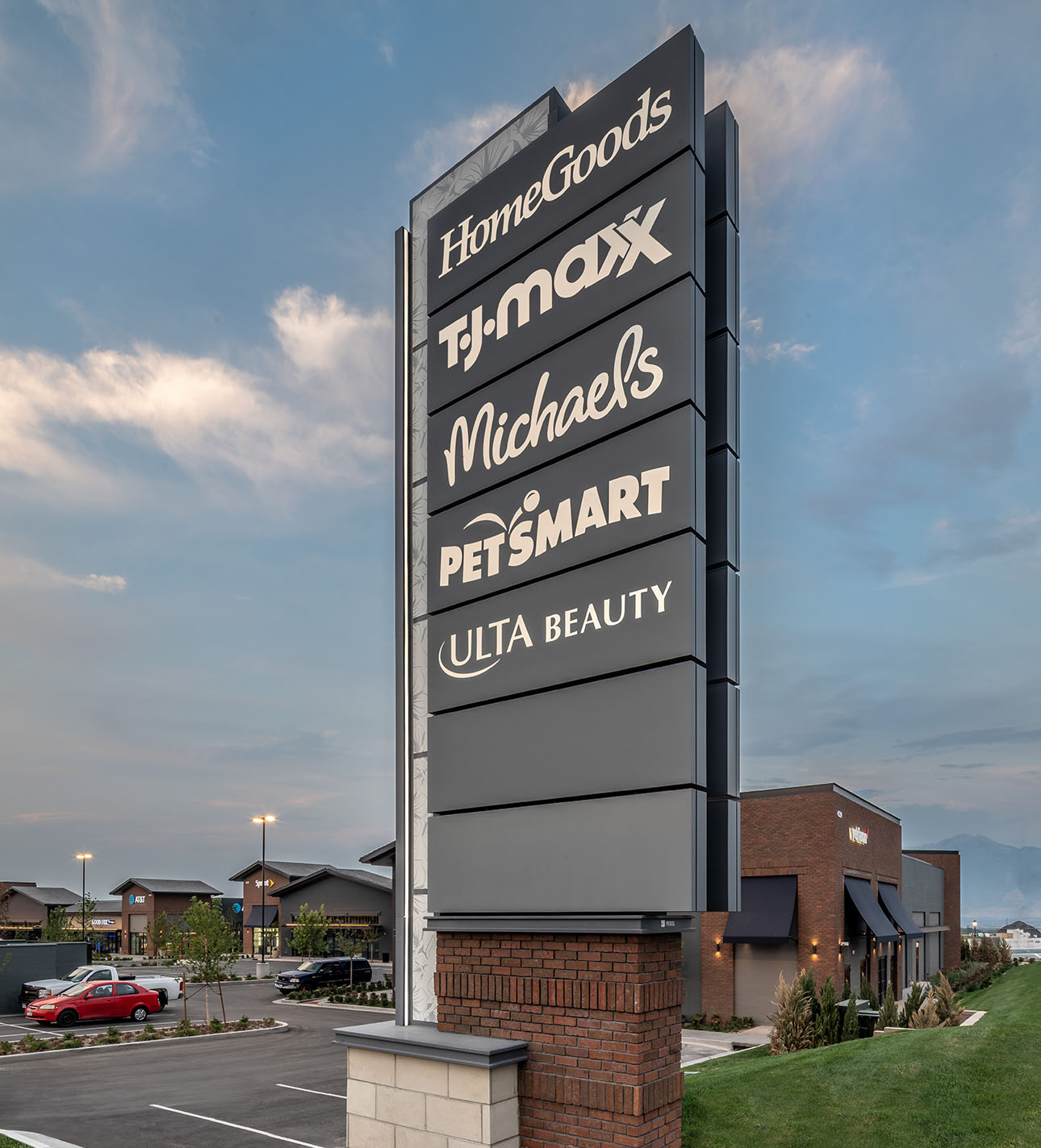 A tall outdoor sign displays store names