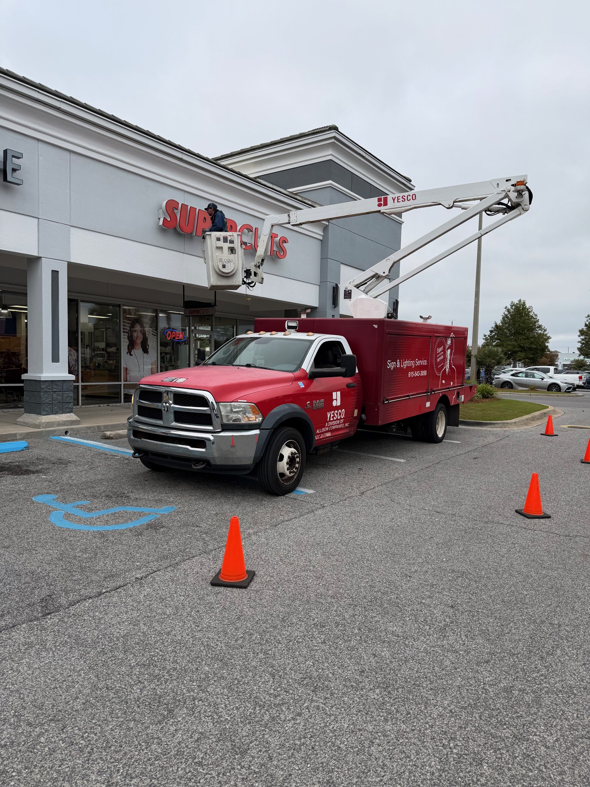 YESCO technicians repair the red illuminated channel letter storefront sign at a Supercuts salon in Destin, Florida