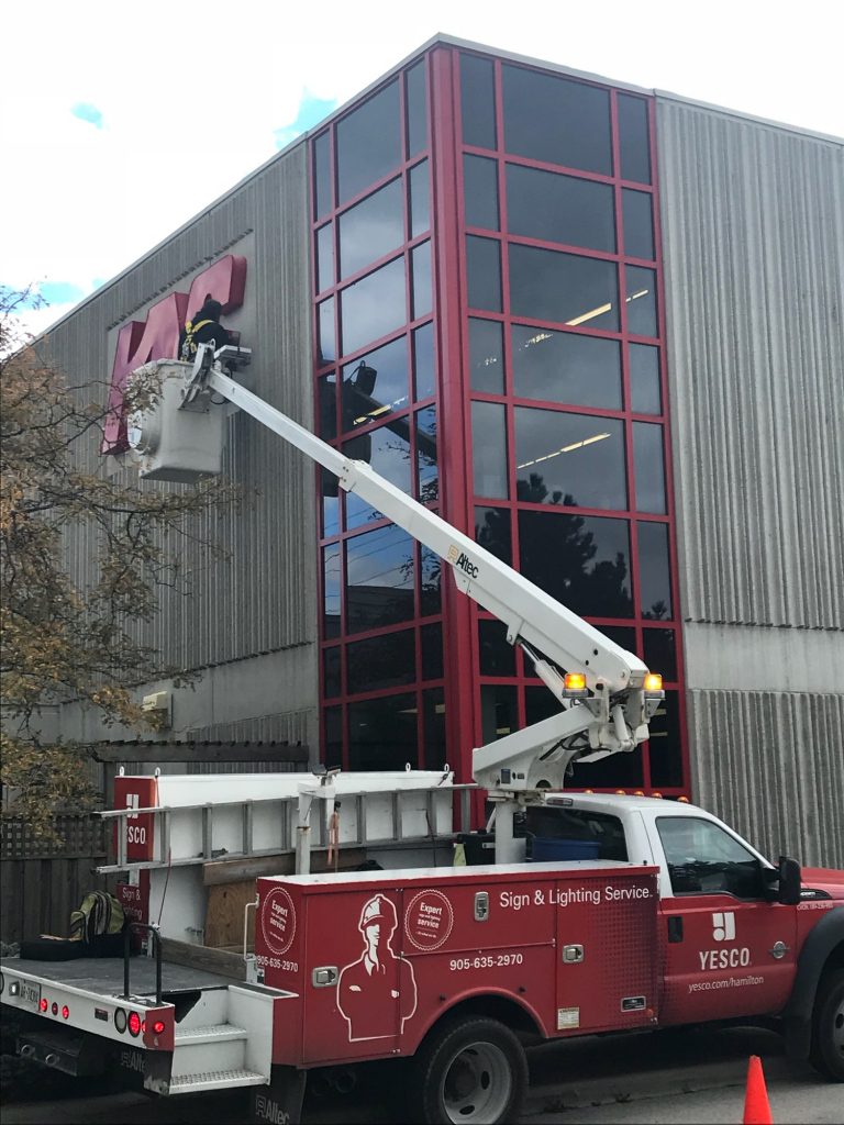 a photo a red YESCO service truck with the bucket ladder at KC Crowder sign.