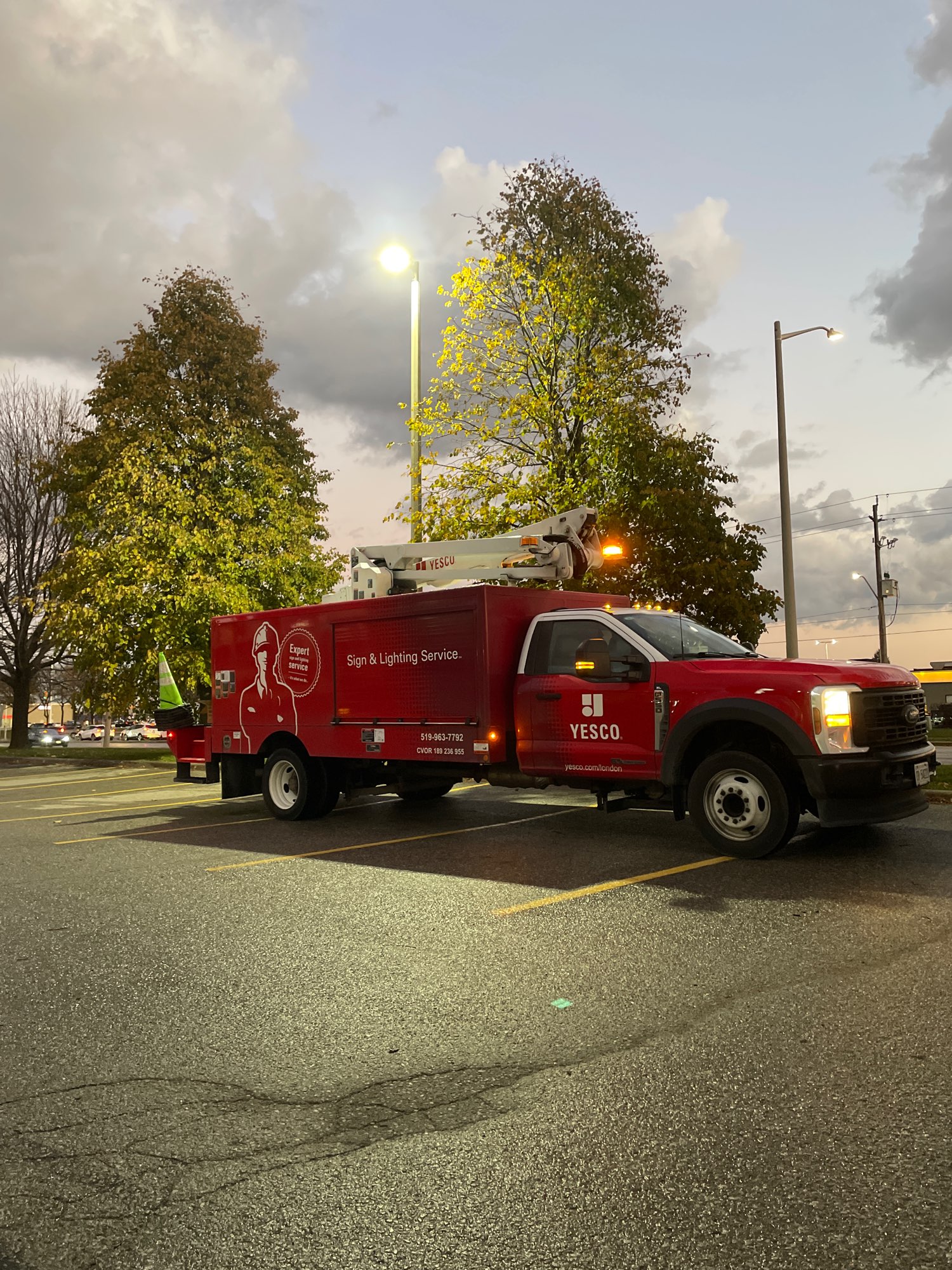 red Yesco lighting truck retrofitting a pole light