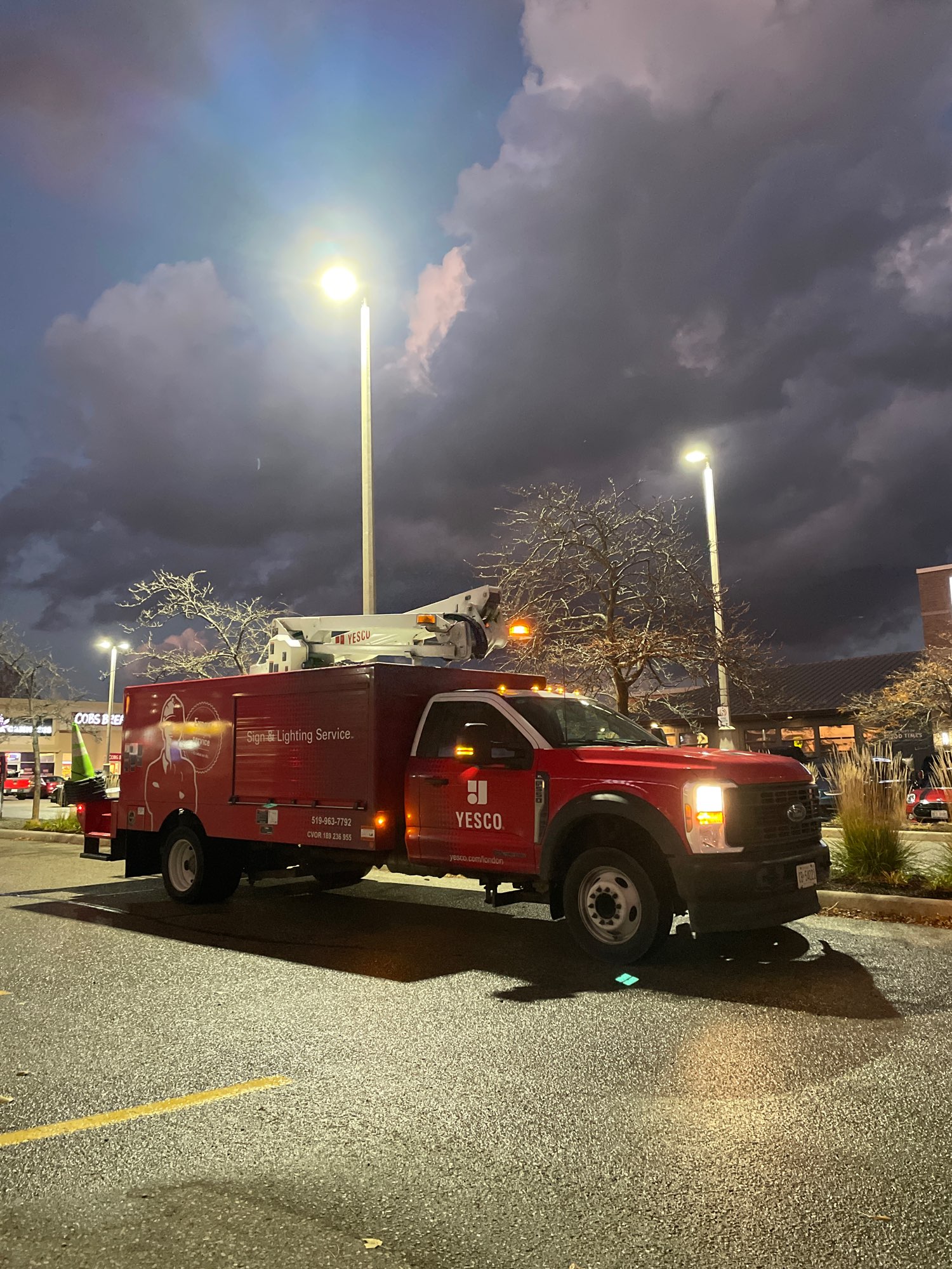 red Yesco lighting truck retrofitting a pole light