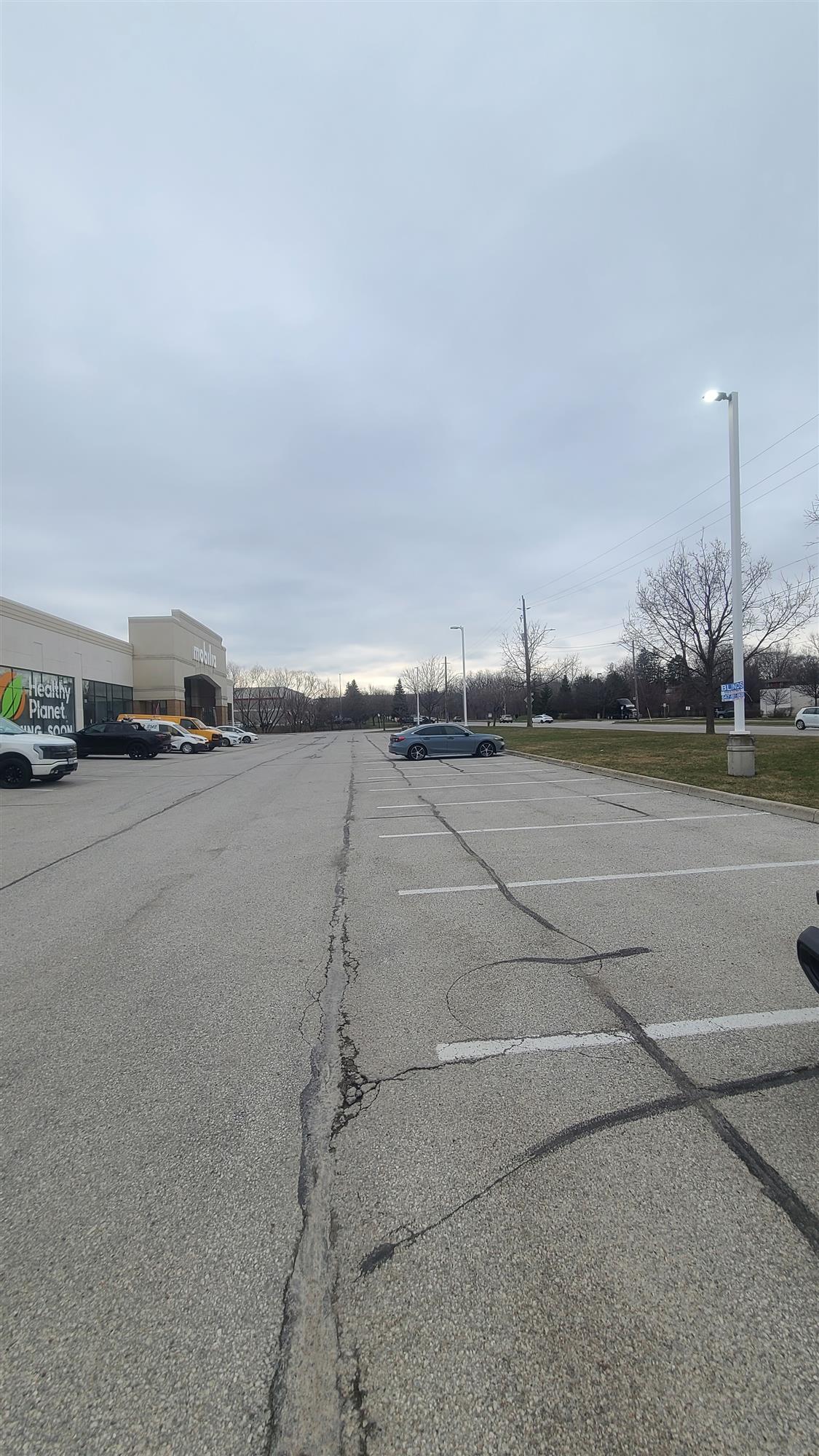 a parking lot with cars and an illuminated pole light