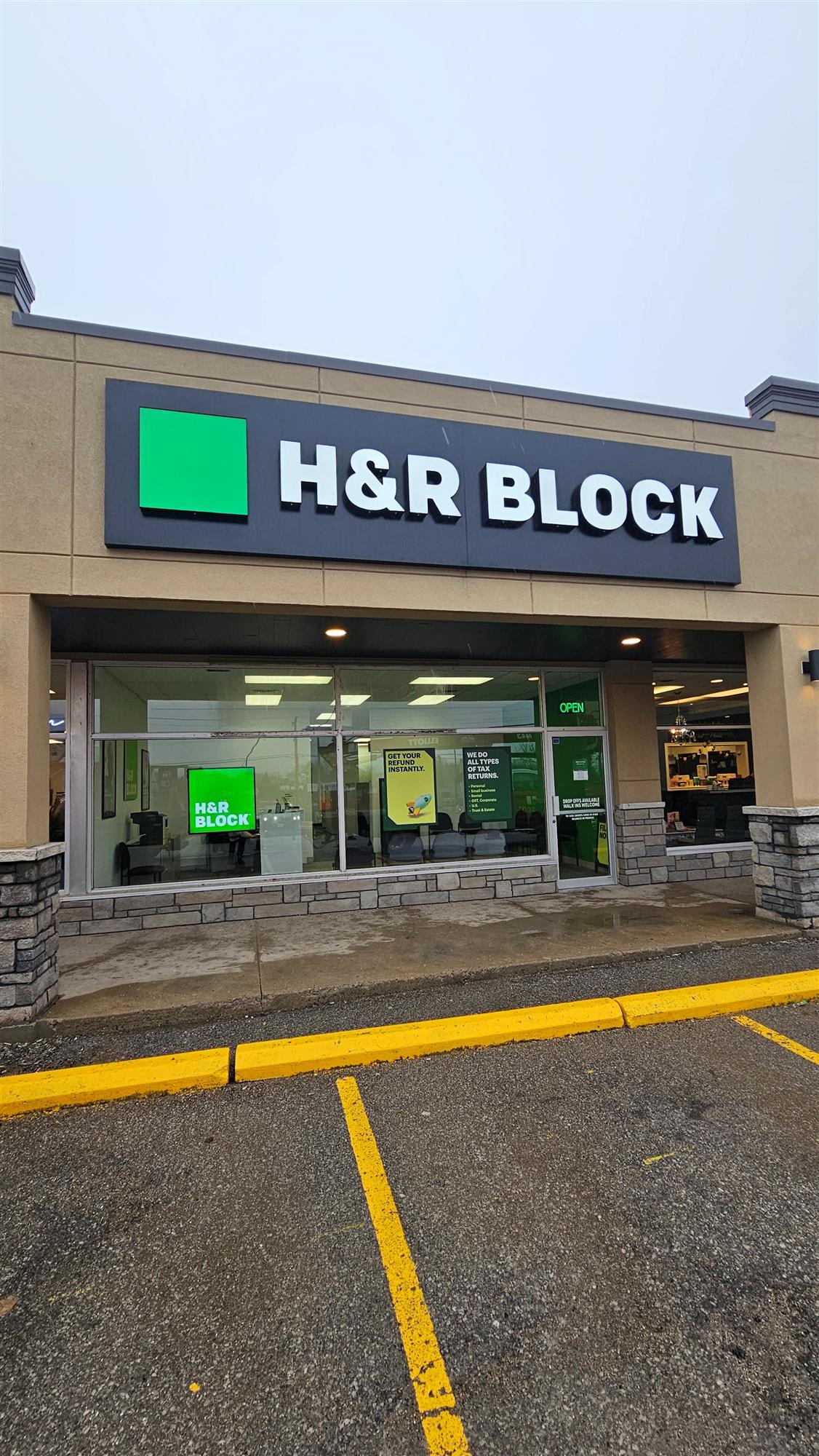 and black and green sign for H and R Block above the store