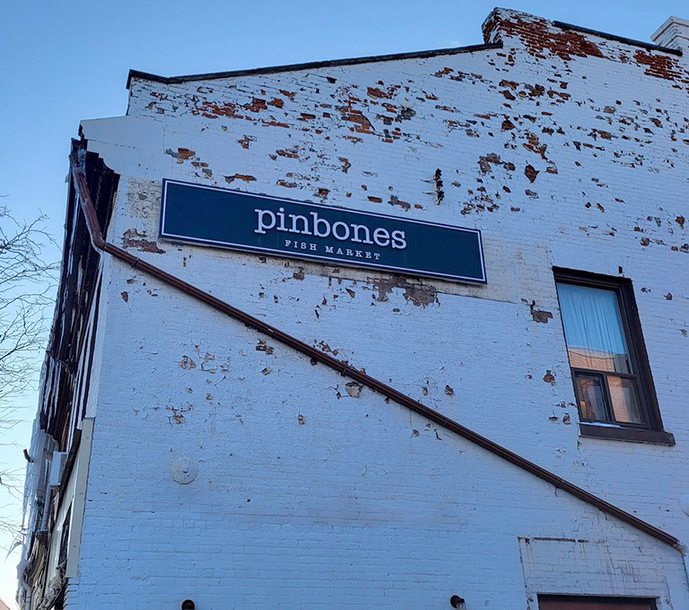 an old brick building painted white with a blue and white sign Pinebones fish market