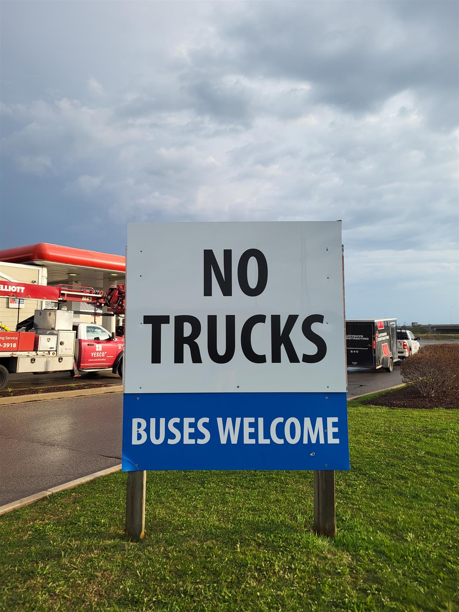 a white and blue sign that reads No trucks buses welcome