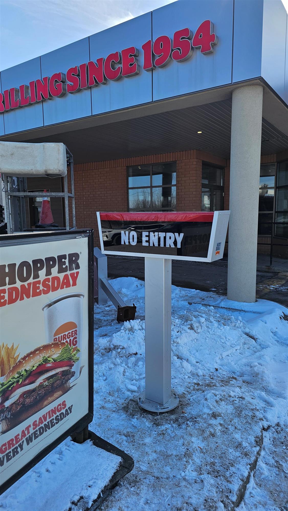 a black, red and silver no entry sign in front of Burger King store