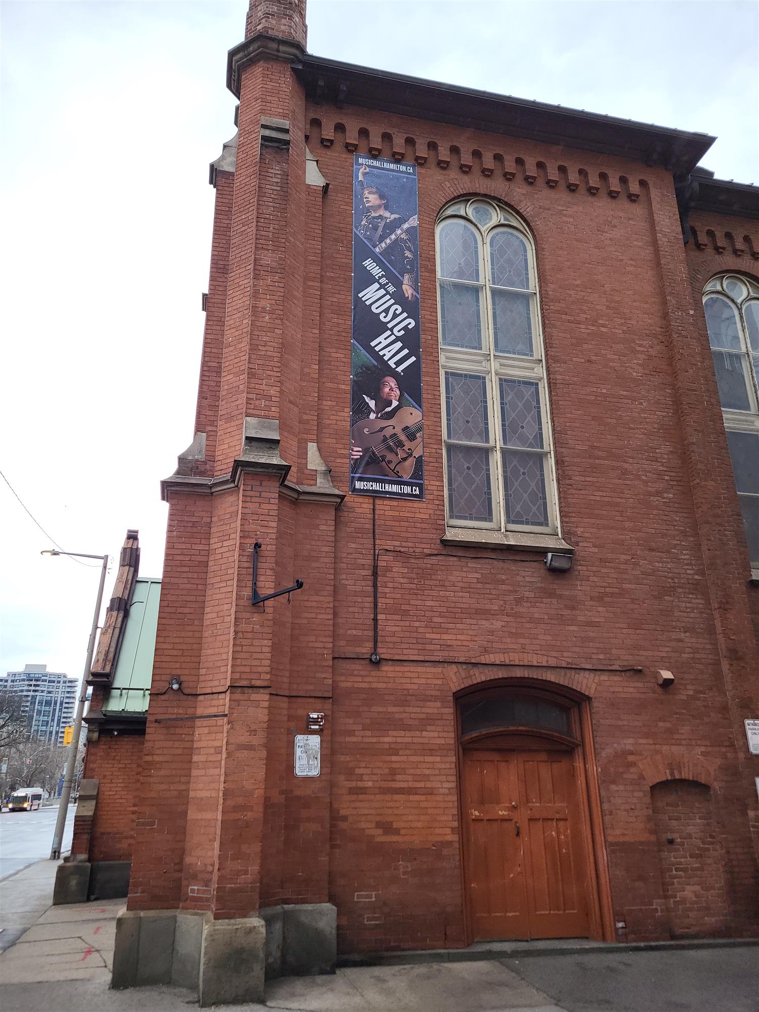 an old brick building with a banner advertising home of the music hall with two musicians faces