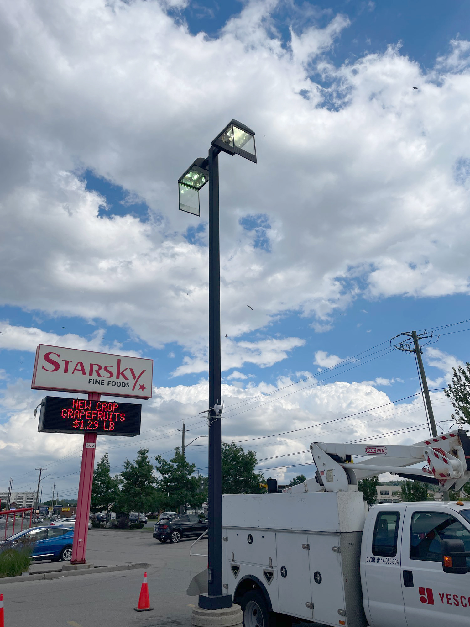 Starsky Fine Foods sign and a parking pole light in the parking lot at Starsky's with a white and red Yesco truck