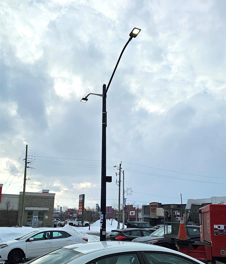 a pole light in a parking lot with cars and a red Yesco truck near