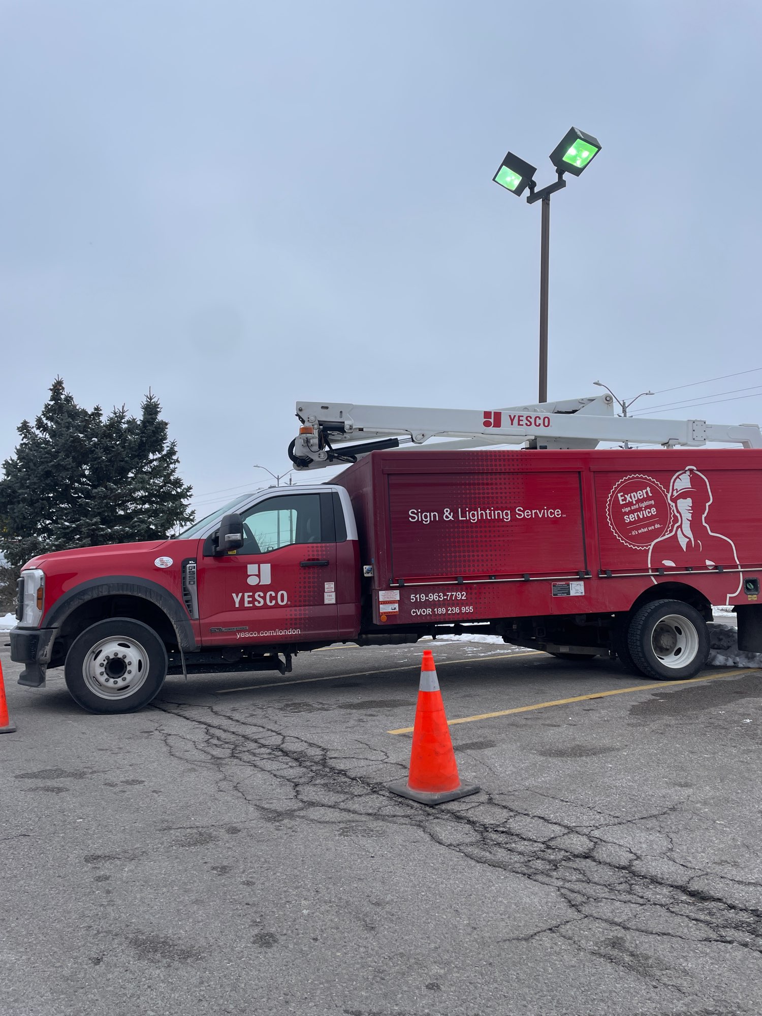 Red Yesco truck beside a parking lot light that is illuminated and repaired