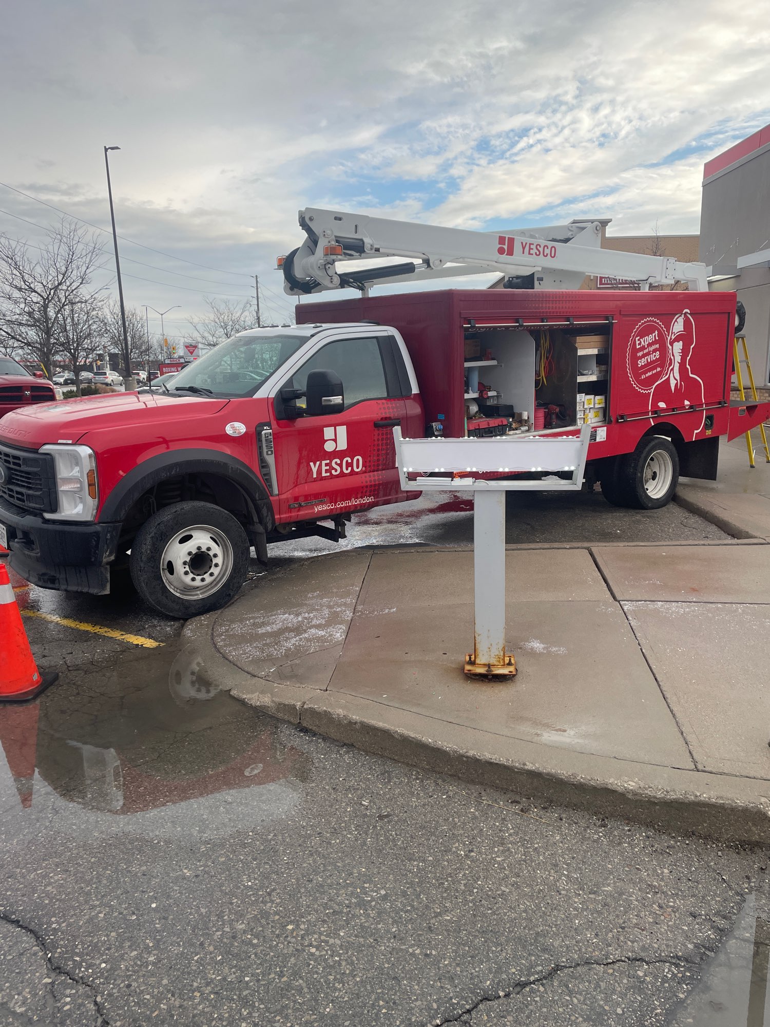 a red Yesco truck beside a drive through sign that is being repaired