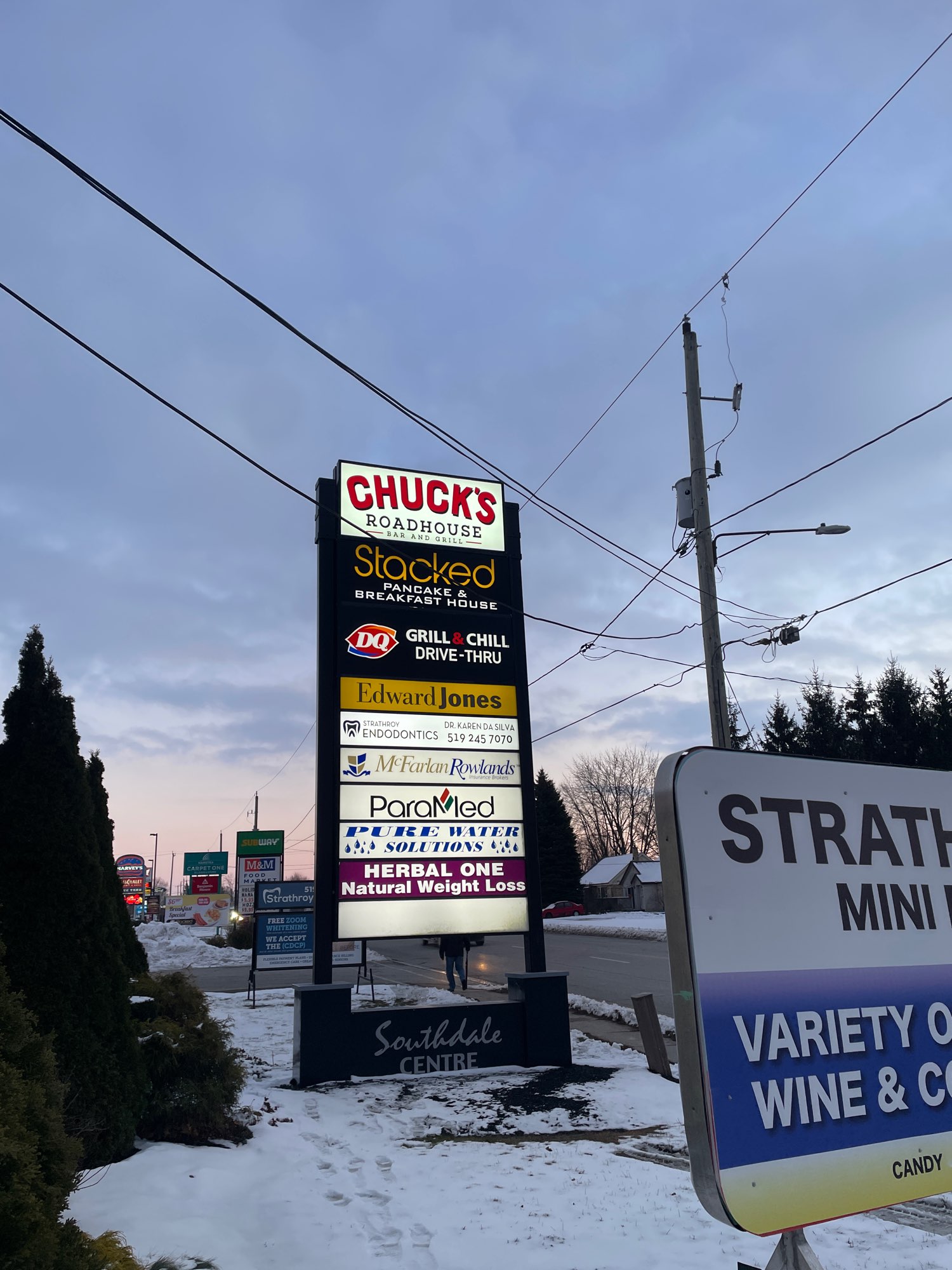 dusk shot of Chuck' Road House pylon sign with many other businesses listed