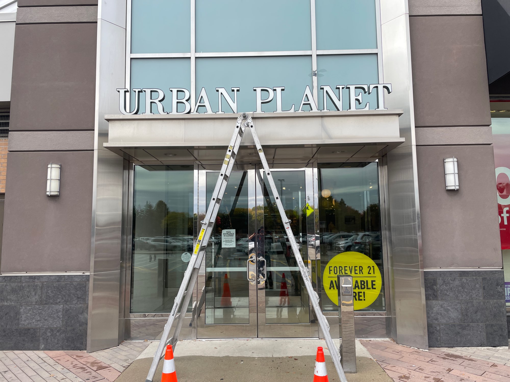 a ladder in front of the Urban Planet sign for sign repair