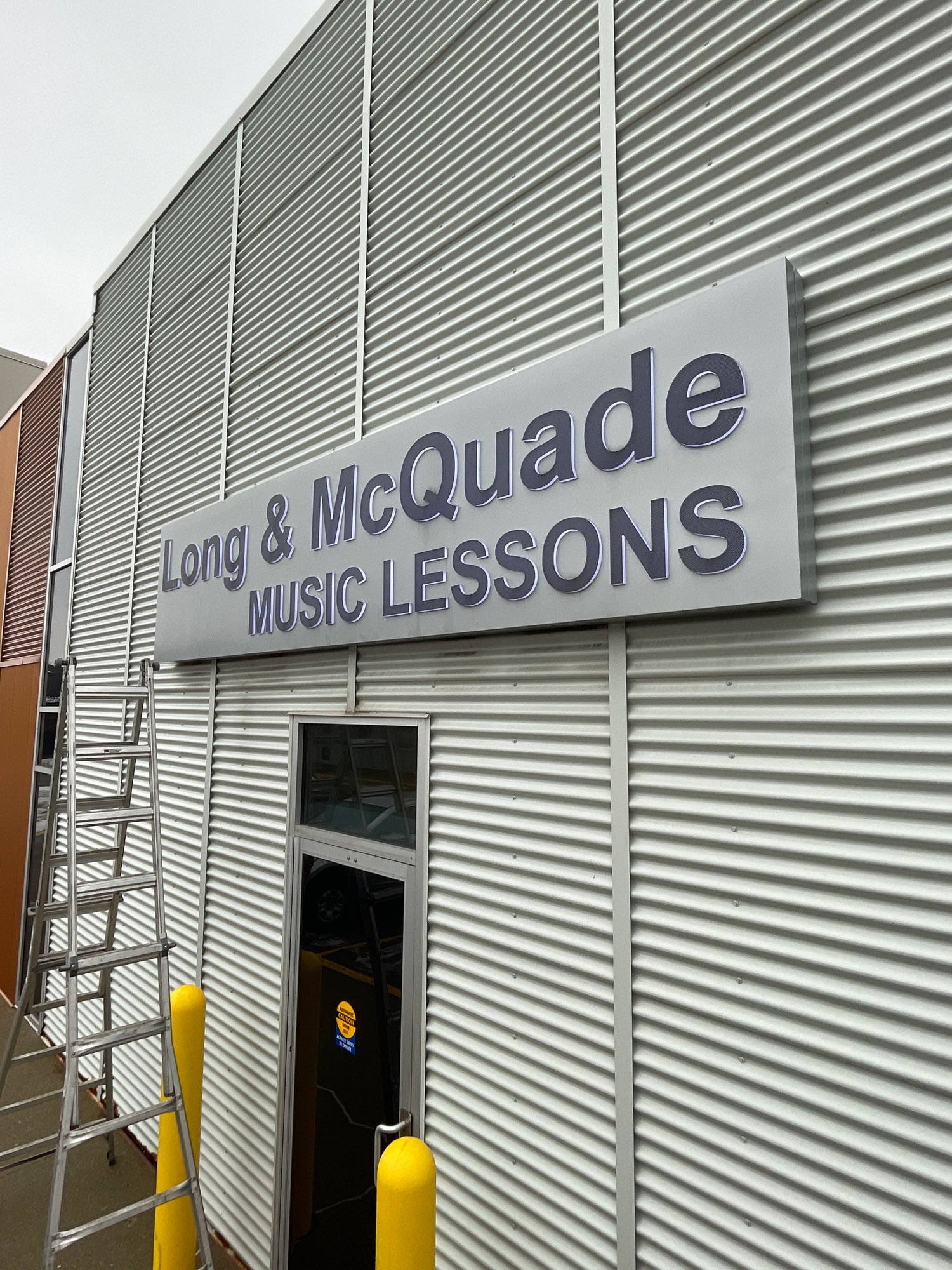 a silver and black Long and McQuade Music Lessons sign
