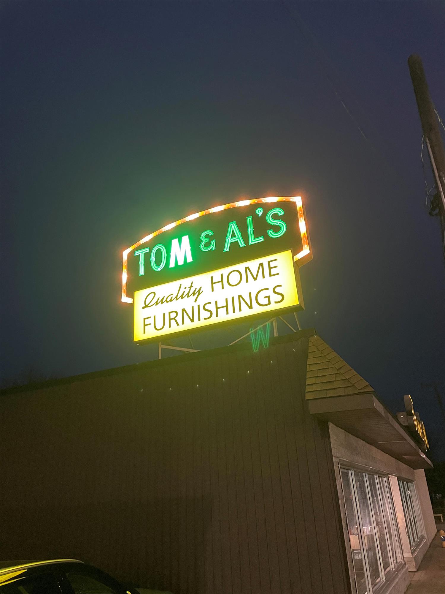 nighttime view of Tom and Al's quality home furnishing sign