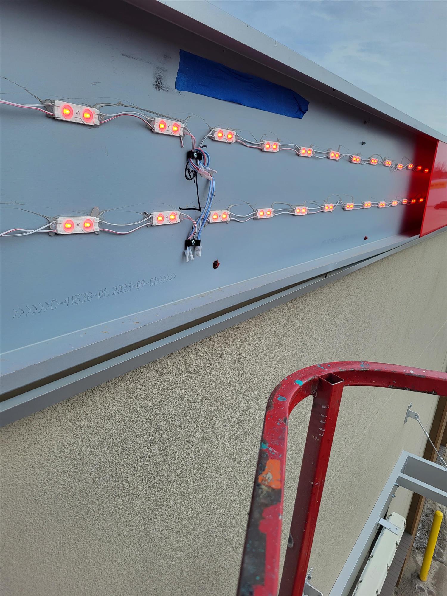 the inside of an red banner showing LED lights that are being repaired to illuminate sign