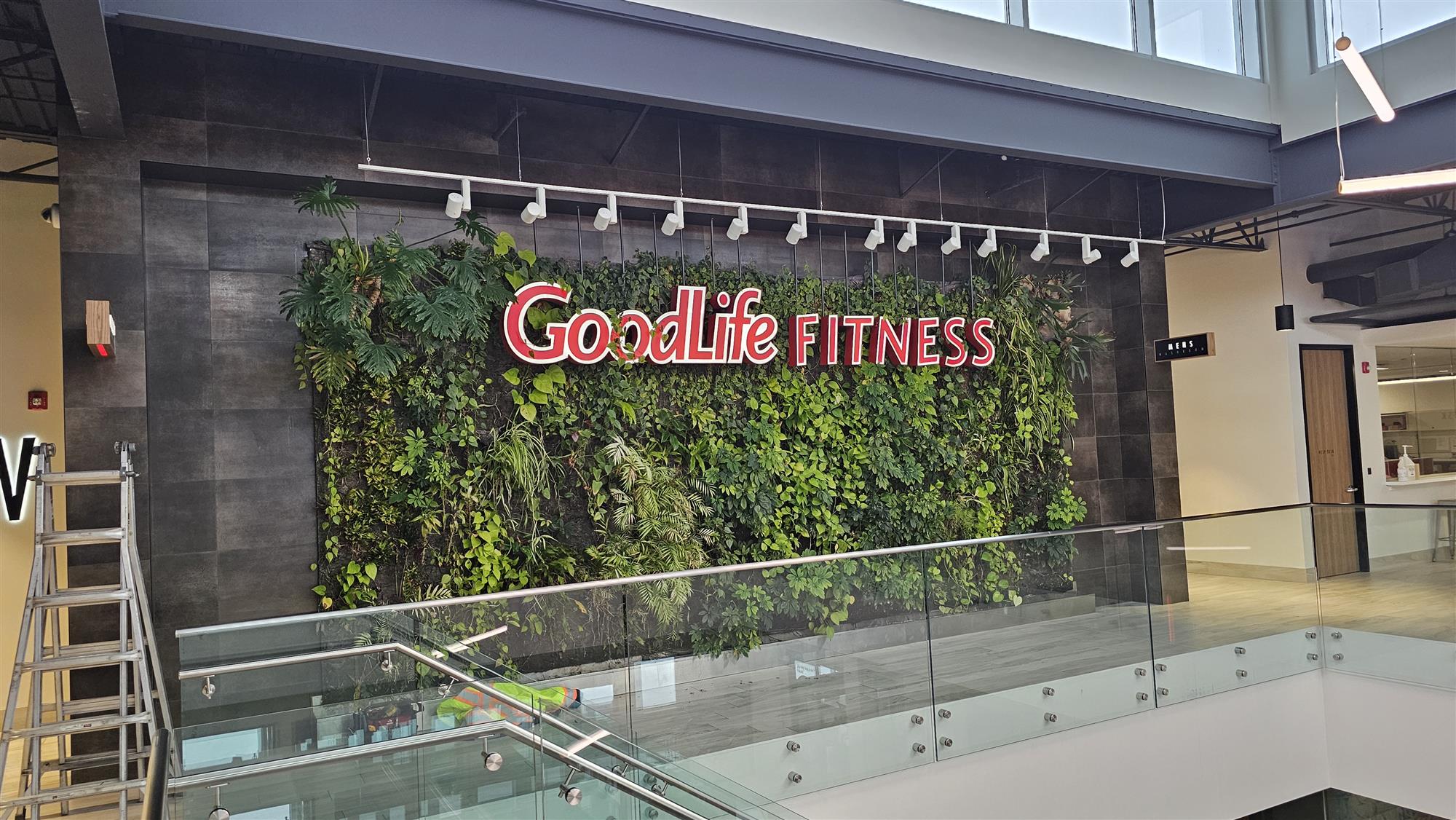 inside a building with a GoodLife Fitness sign in front of a large live wall full of green living plants