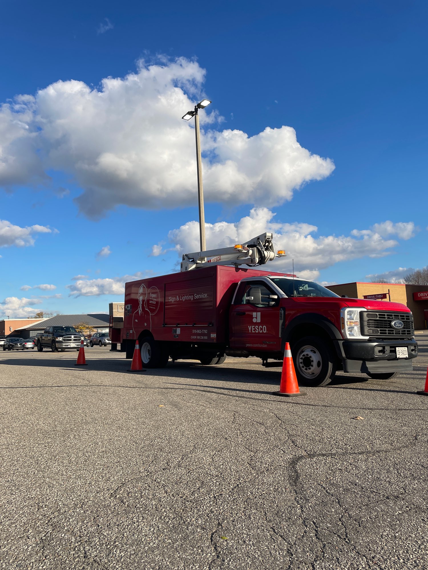 red Yesco service truck replacing a light fixture in the parking lot at London Plaza in London Ontario