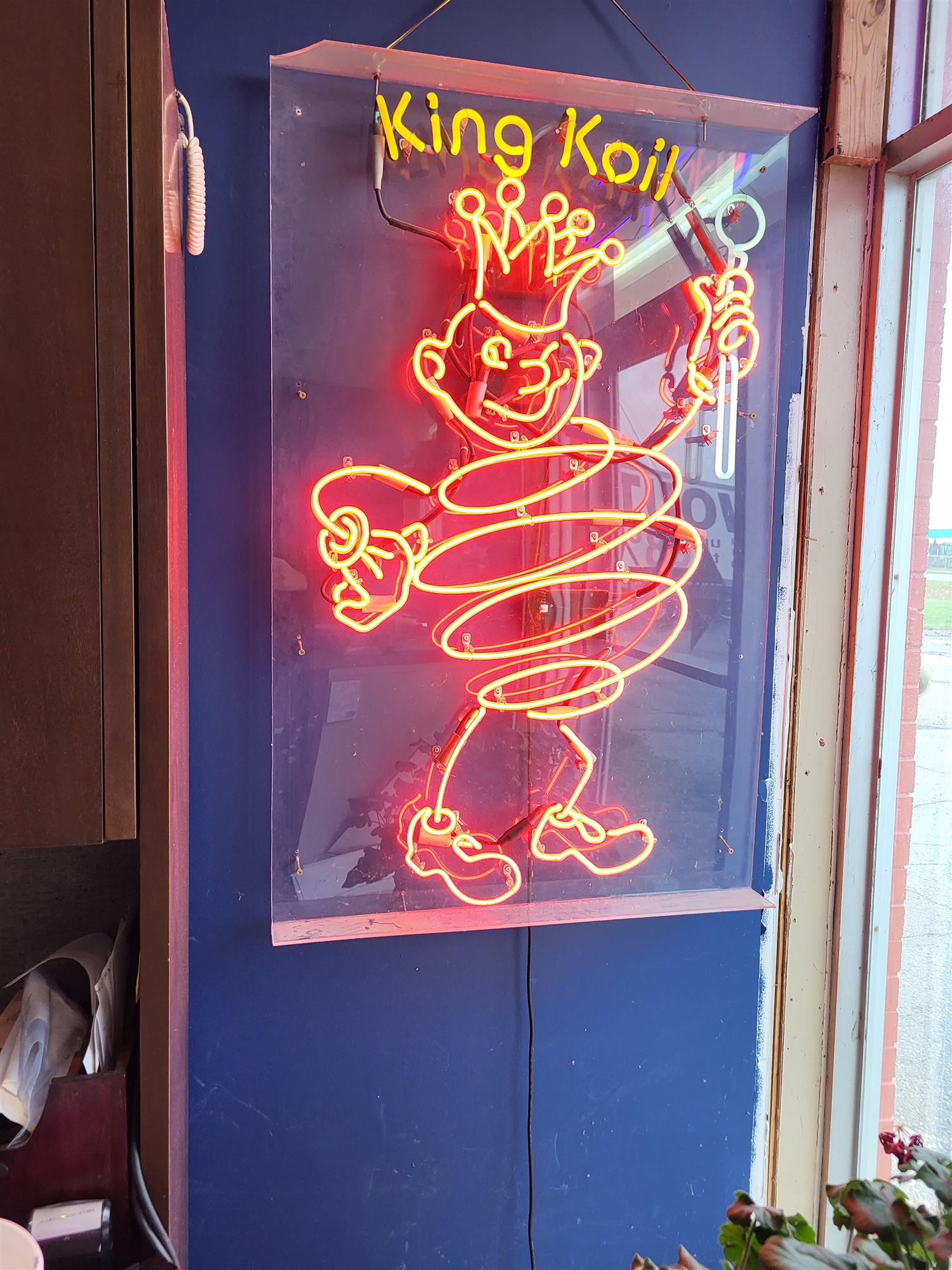 Red neon 'King Koil' sign featuring the King Koil mascot wearing a crown and holding a scepter