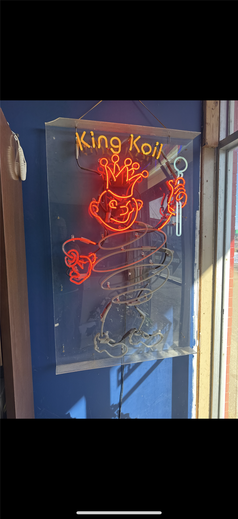 Red neon partially lit 'King Koil' sign featuring the King Koil mascot wearing a crown and holding a scepter
