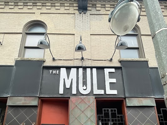 a black and white store sign on a an old bricked building for the Mule restaurant
