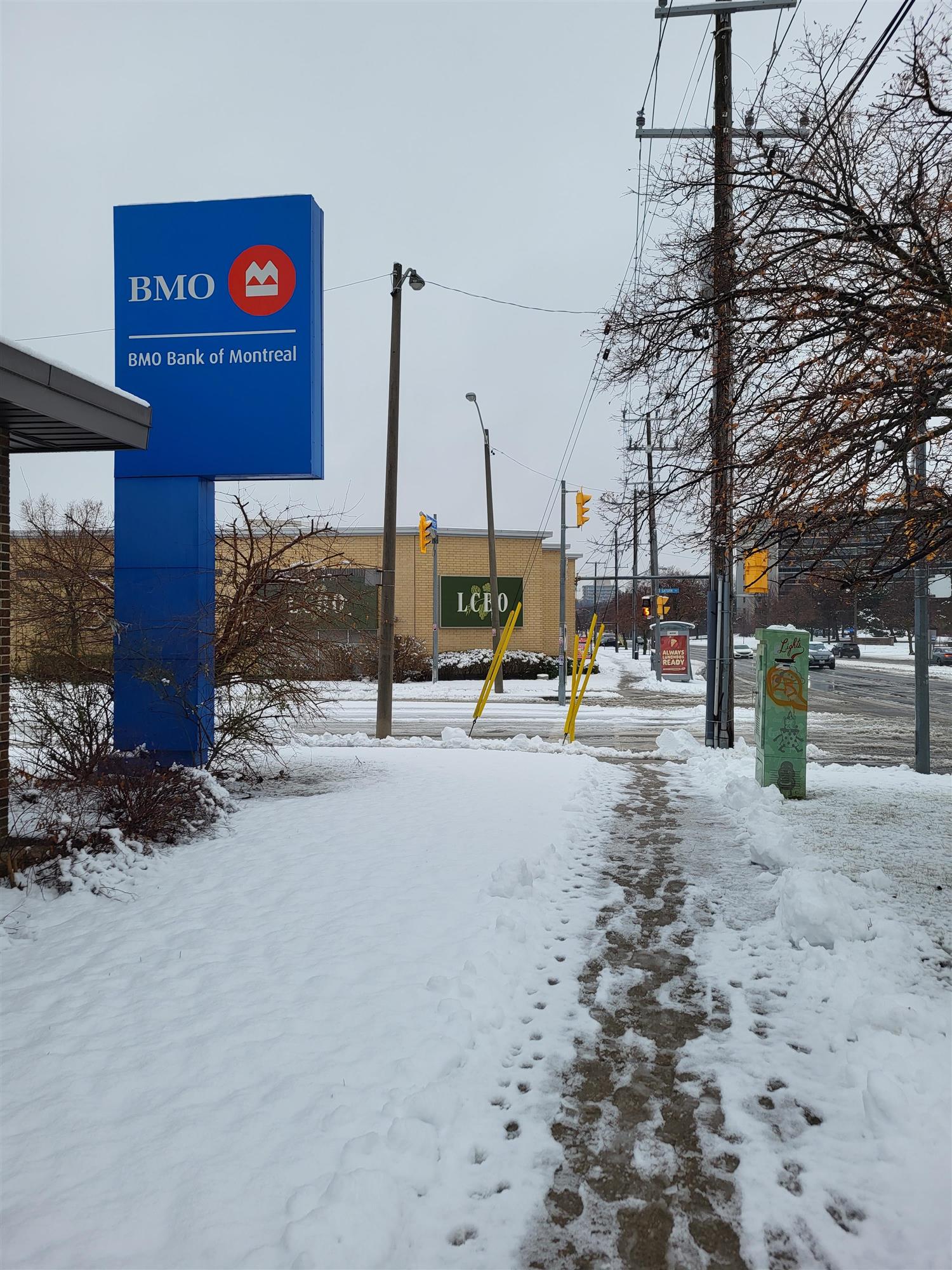 a red and white and blue BMO sign at front of bank with snow on ground
