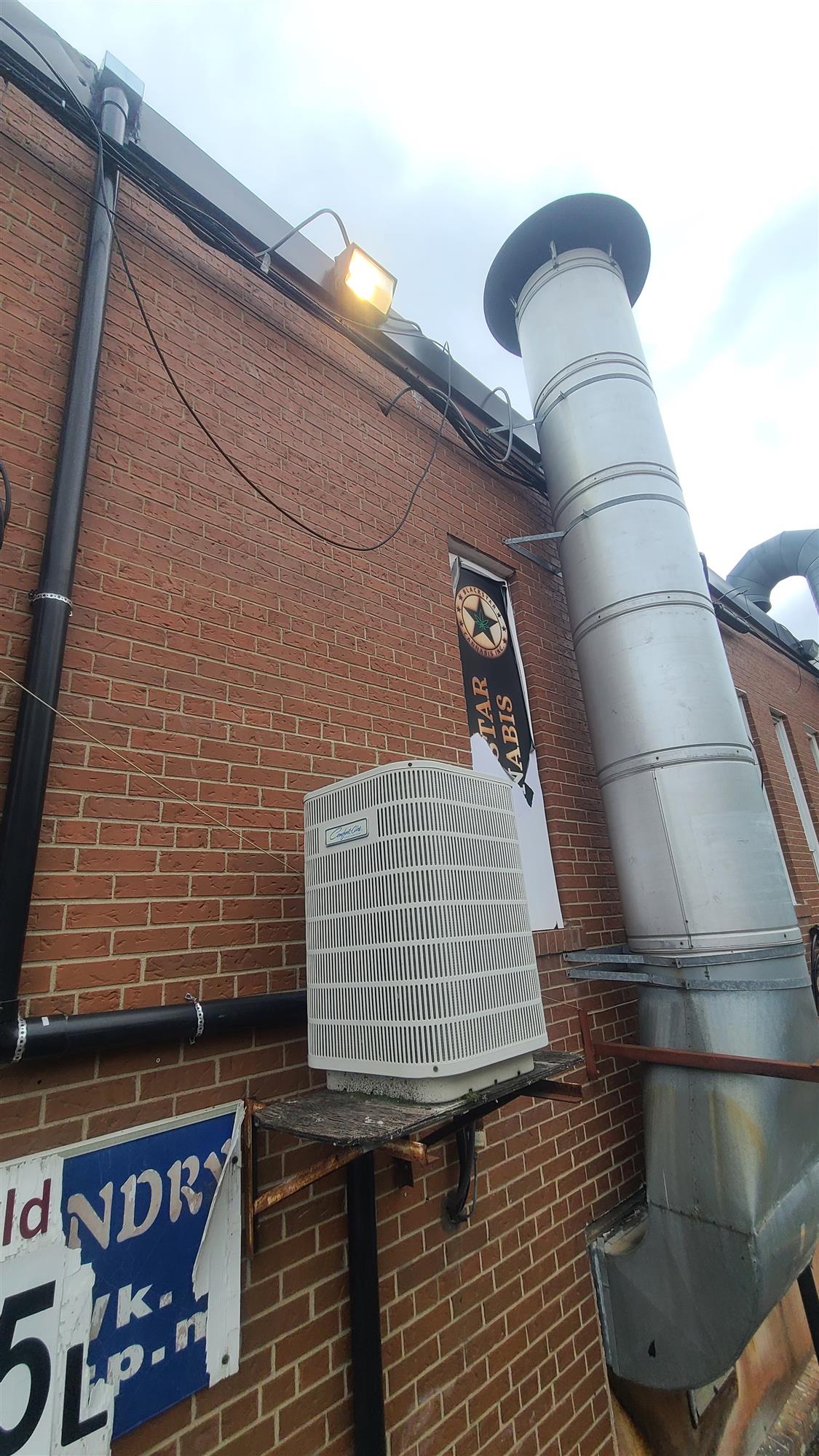 a silver exhaust chimney running up the side of a red brick building