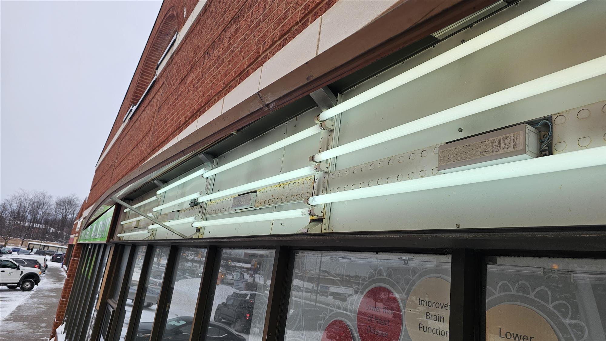 the inside of a horizontal sign above the store entrance that shows florescence lighting tubes