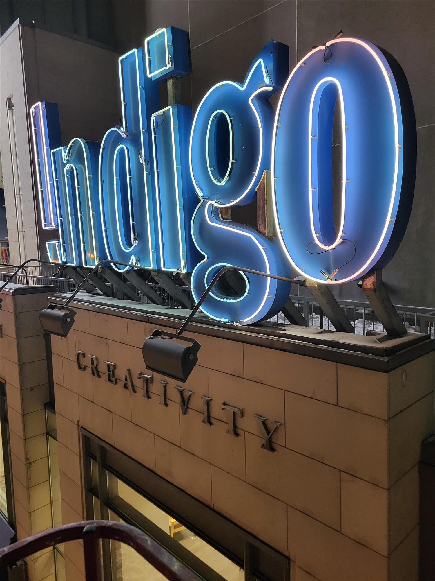 a blue neon sign for Indigo book store above the store entrance