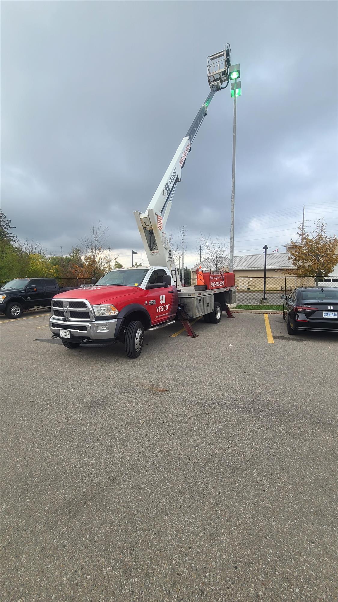 a red Yesco truck beside a Polelight that is being repaired