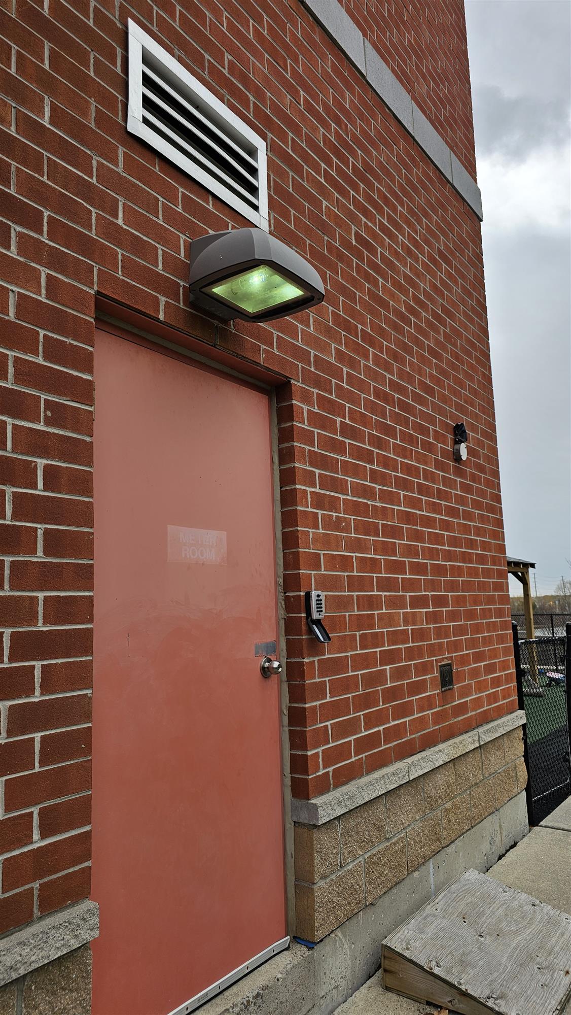 a red brick building with a bright wall pack light over door