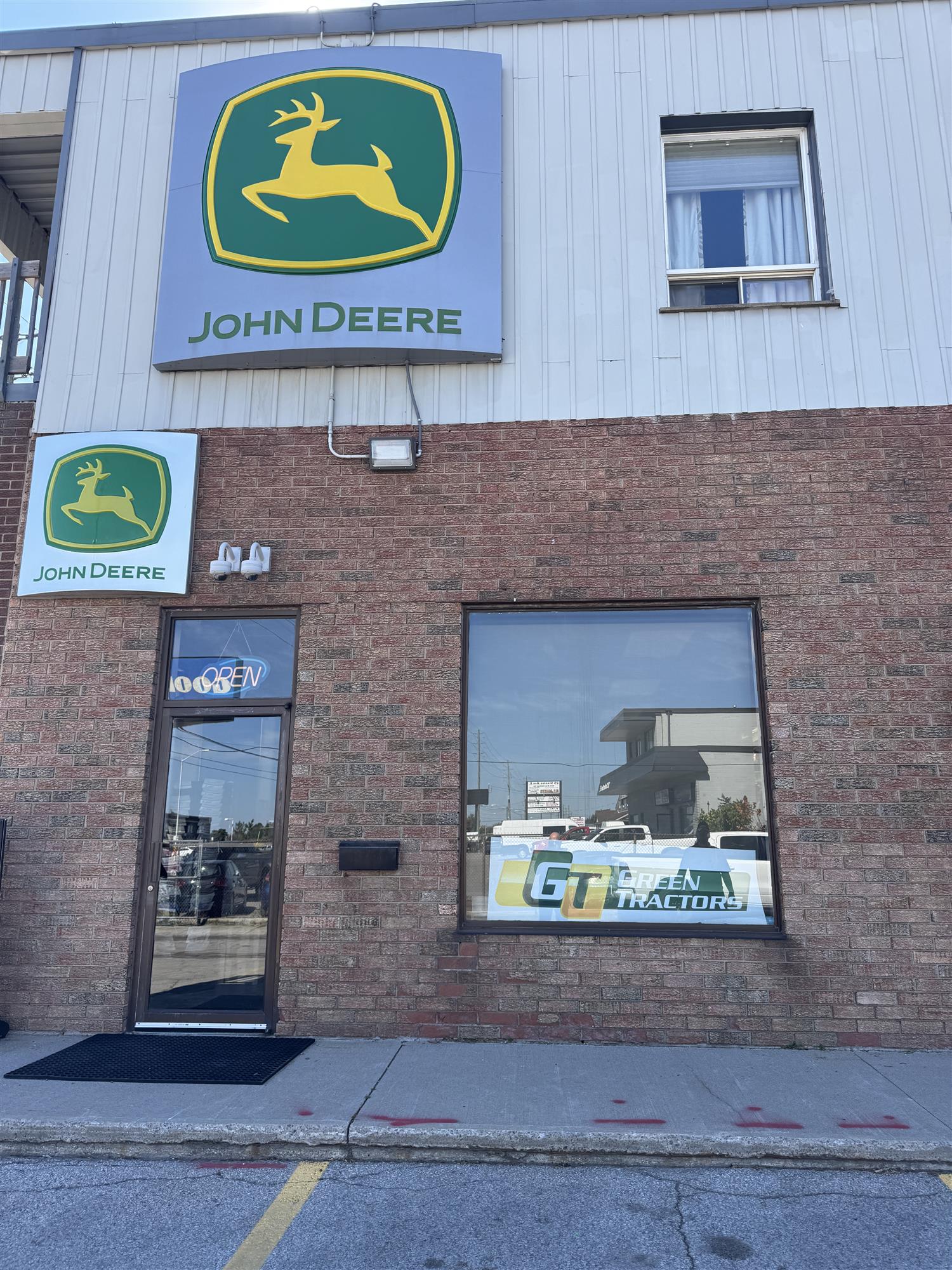 two John Deere signs on the side of brick building