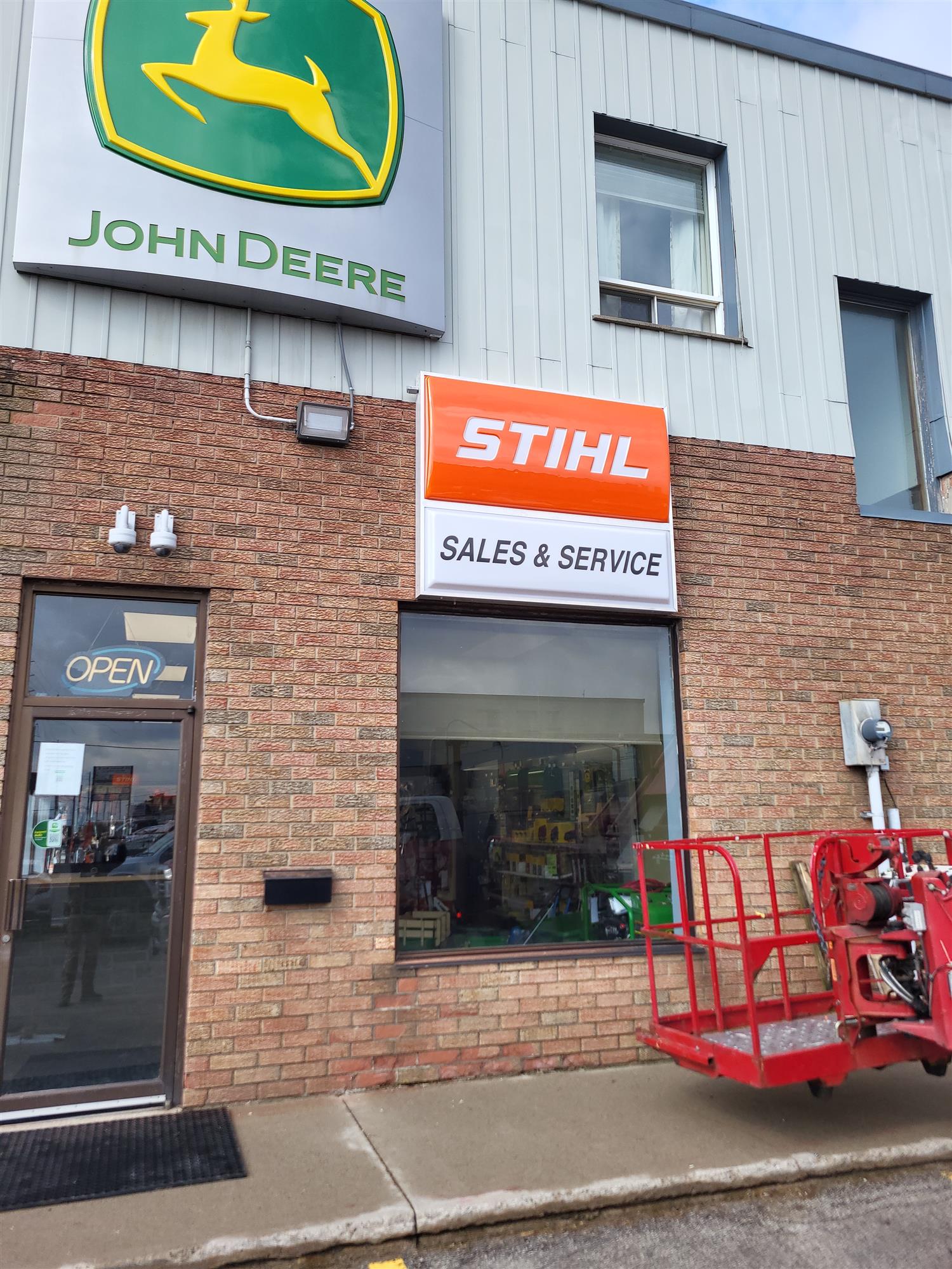 a John Deere and Stihl sign on side of brick building