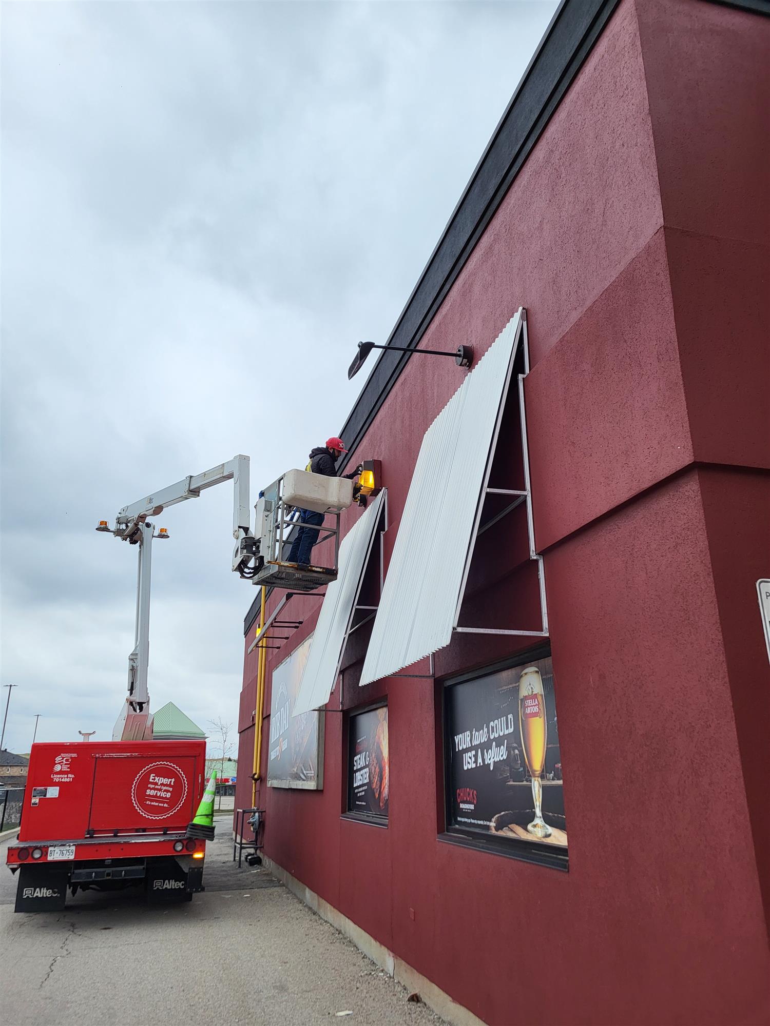 a red stucco building with lights being repaired