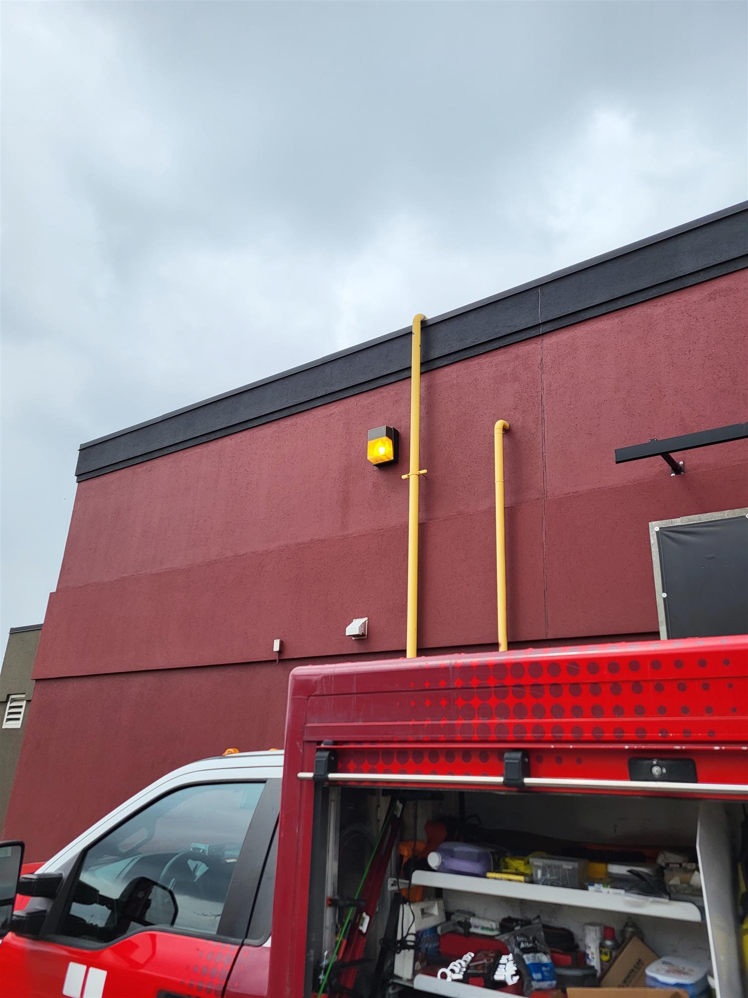 a red building with a wall light and truck in front