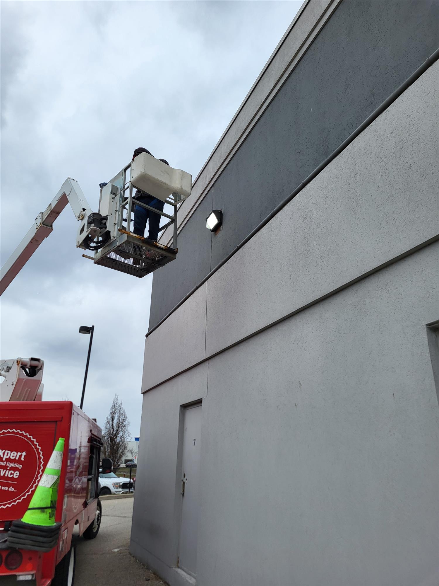 a grey building with a buck ladder beside the wall light for repair