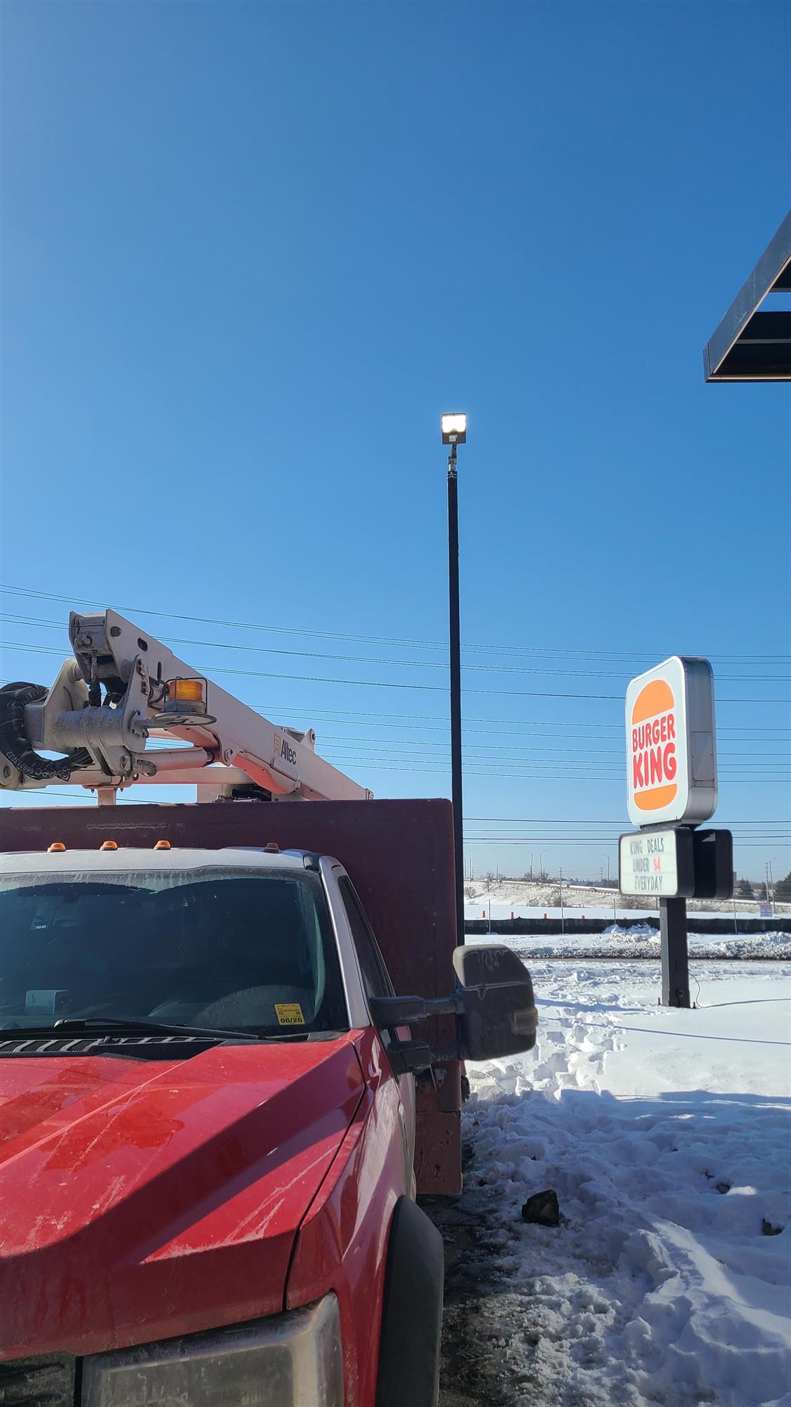a red Yesco truck in front of a Burger King sign and pole light
