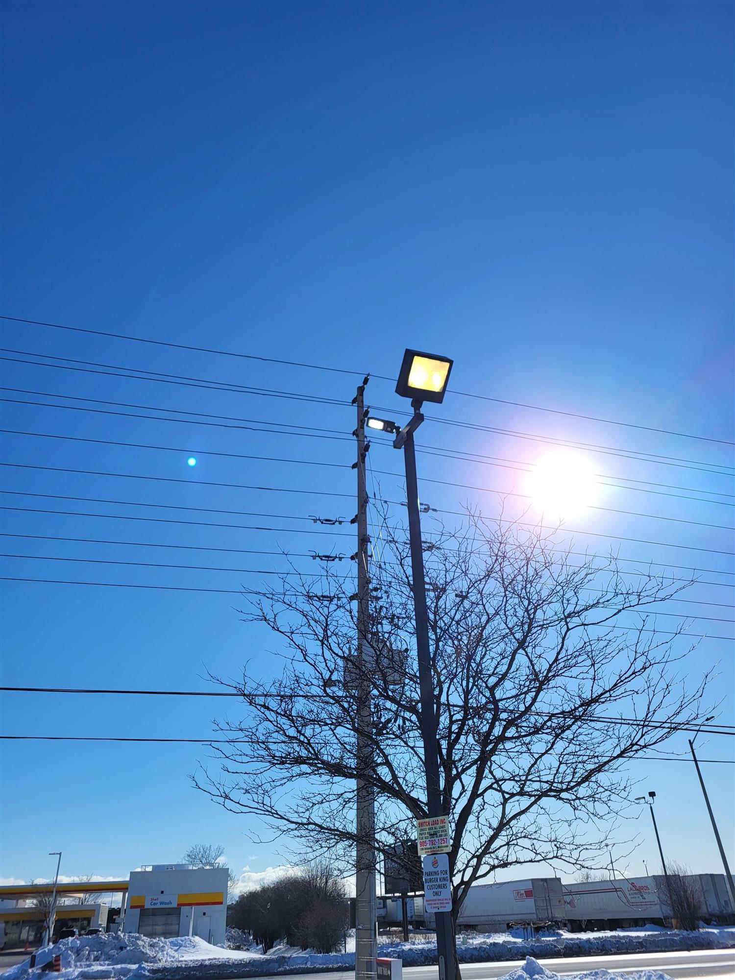 a bright sunny day with blue sky and a parking lot pole light