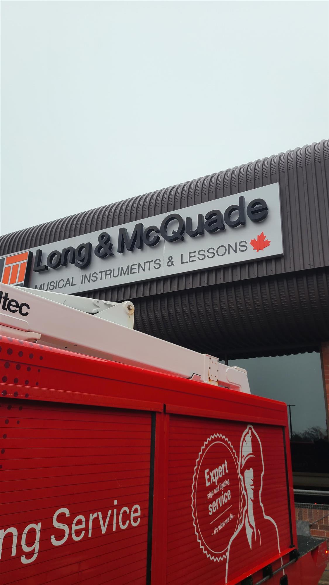 a red Yesco service truck fixing Long and McQuade sign