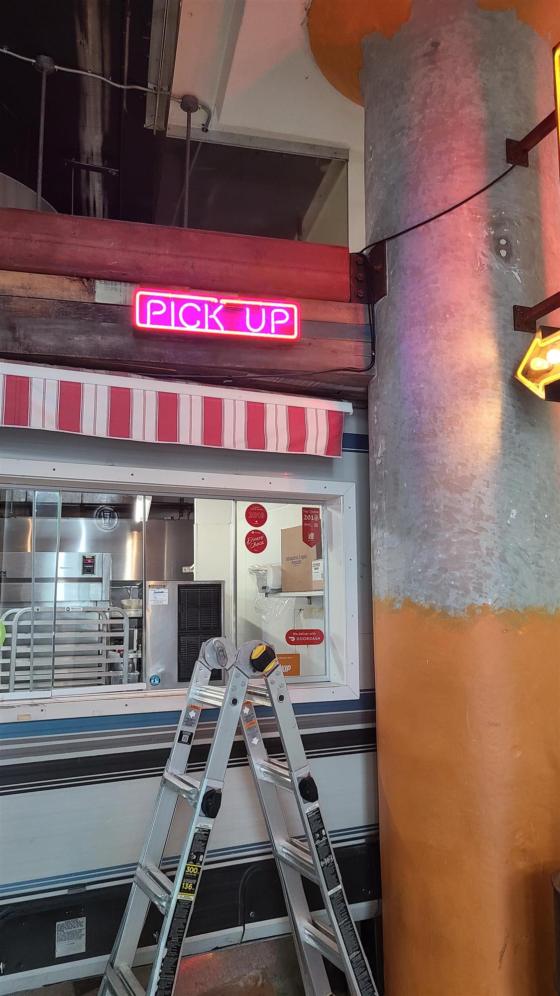 a pink neon sign inside Joe Bird restaurant that says pick up