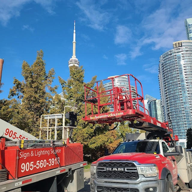 two red Yesco bucket trucks with a tree and the CN tower in the background with a bright blue sky