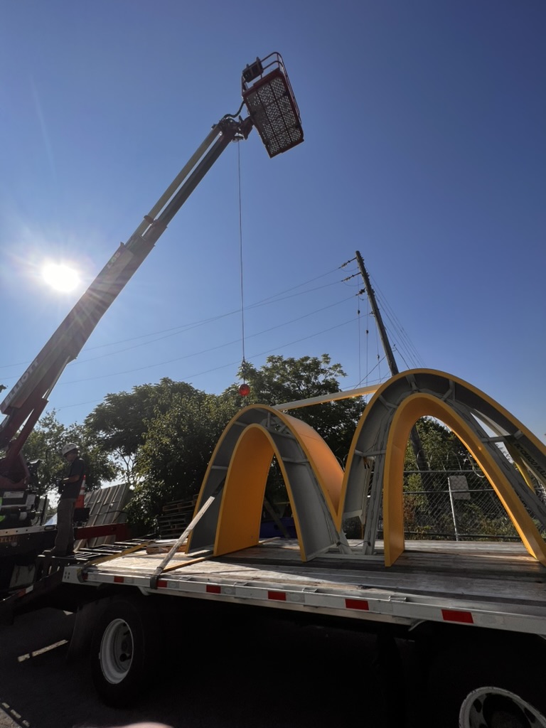 Arriving on site: a set of fabricated McDonald's Golden Arches, ready for installation. Precision hoisting: YESCO technicians guide the Arches into position atop the pylon frame.