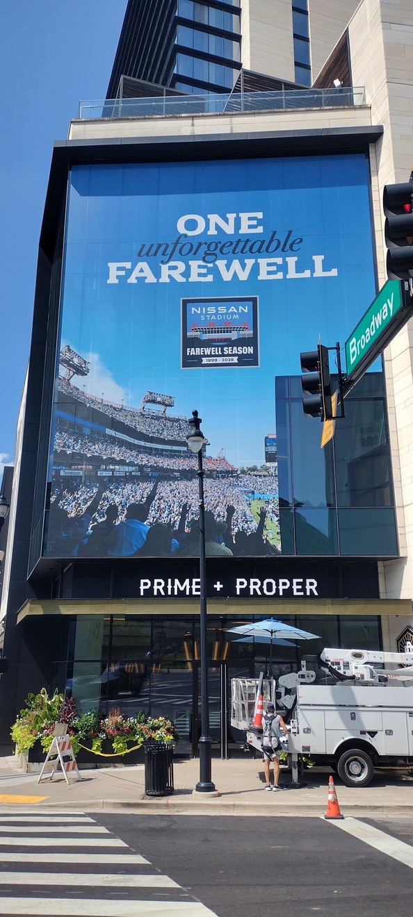Perforated vinyl window graphic for the Tennessee Titans Farewell Season installed on Broadway in Nashville above Prime + Proper with a lift in the street