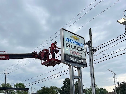a Yesco technician in a bucket truck servicing a large Chevrolet Buick GMC Reaume pylon sign
