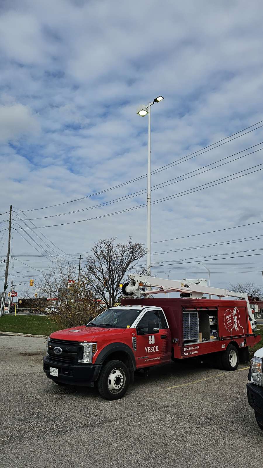 a red yesco service truck parked in a parking lot beside a pole light