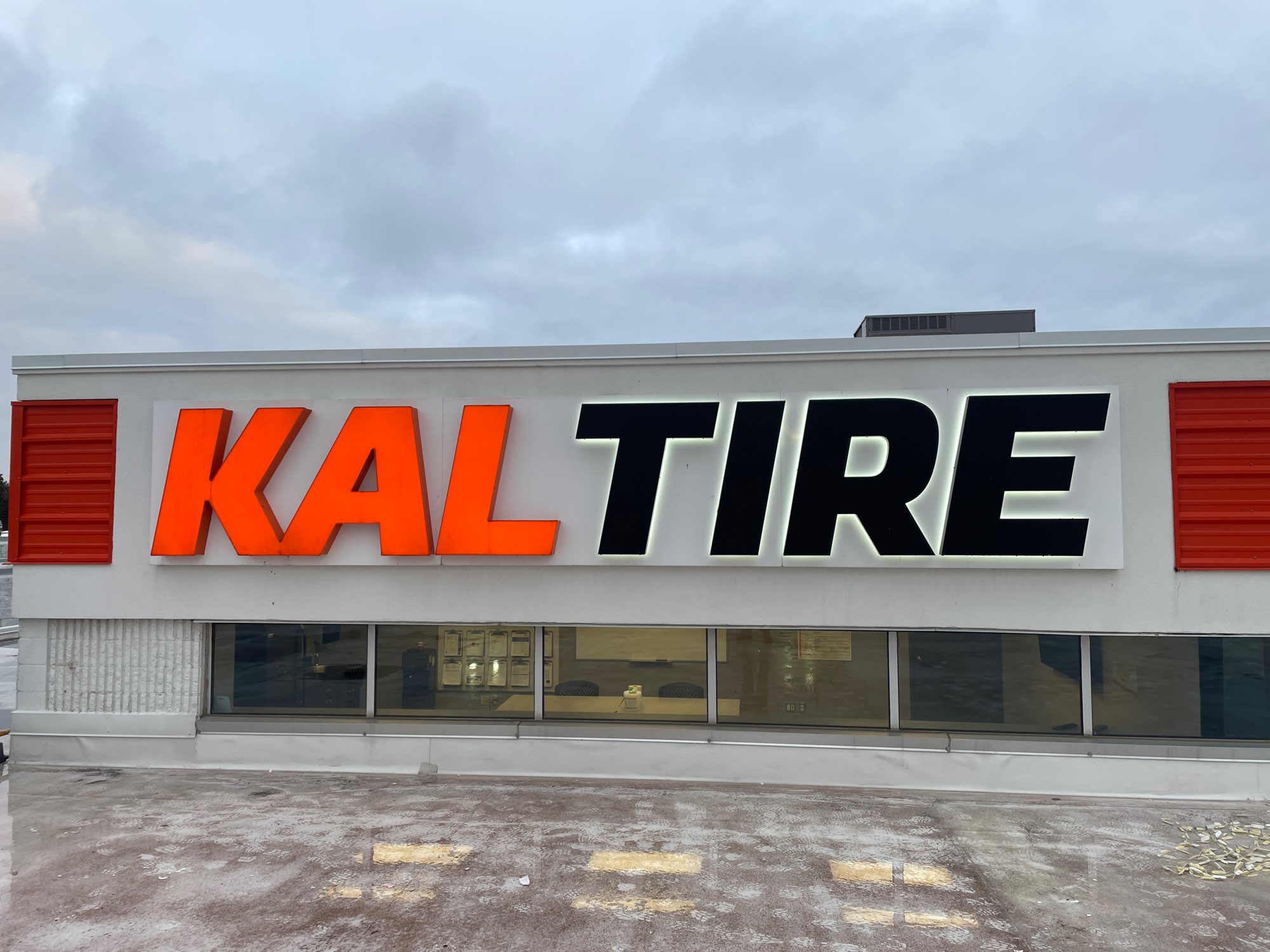 a large outdoor red and black illuminated sign for Kal Tire