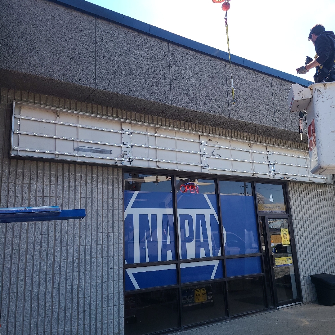 a Yesco technician working on Napa Auto Parts sign in a bucket truck
